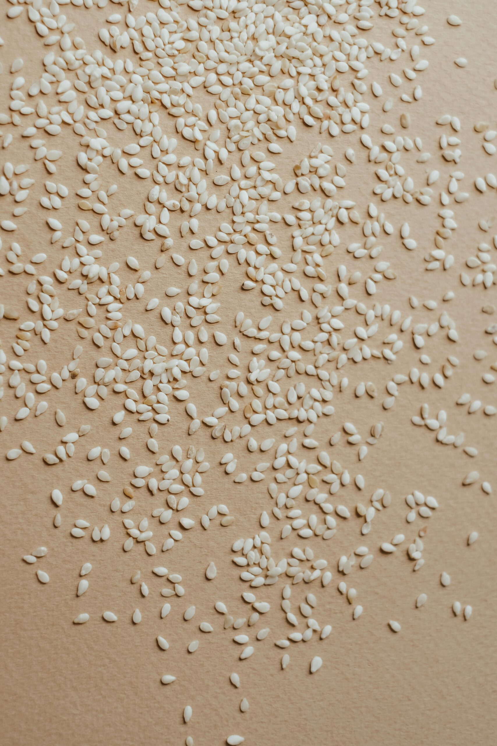 A close-up view of organic raw sesame seeds scattered on a surface, ideal for nutrition concepts.
